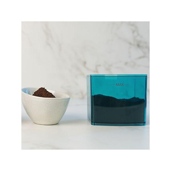 Miska z fusami kawy i niebieski pojemnik wypełniony fusami kawy na białej marmurowej powierzchni.