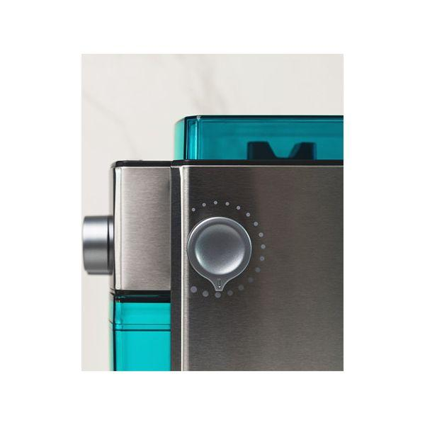 Zbliżenie młynka do kawy z turkusową górą. Młynek jest metaliczny z pokrętłem.