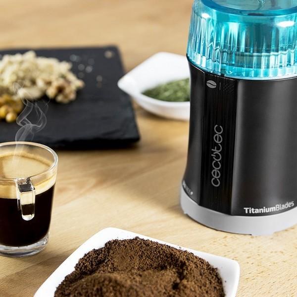 Kaffeemühle mit Kaffee und Zubehör auf einem Holztisch.
