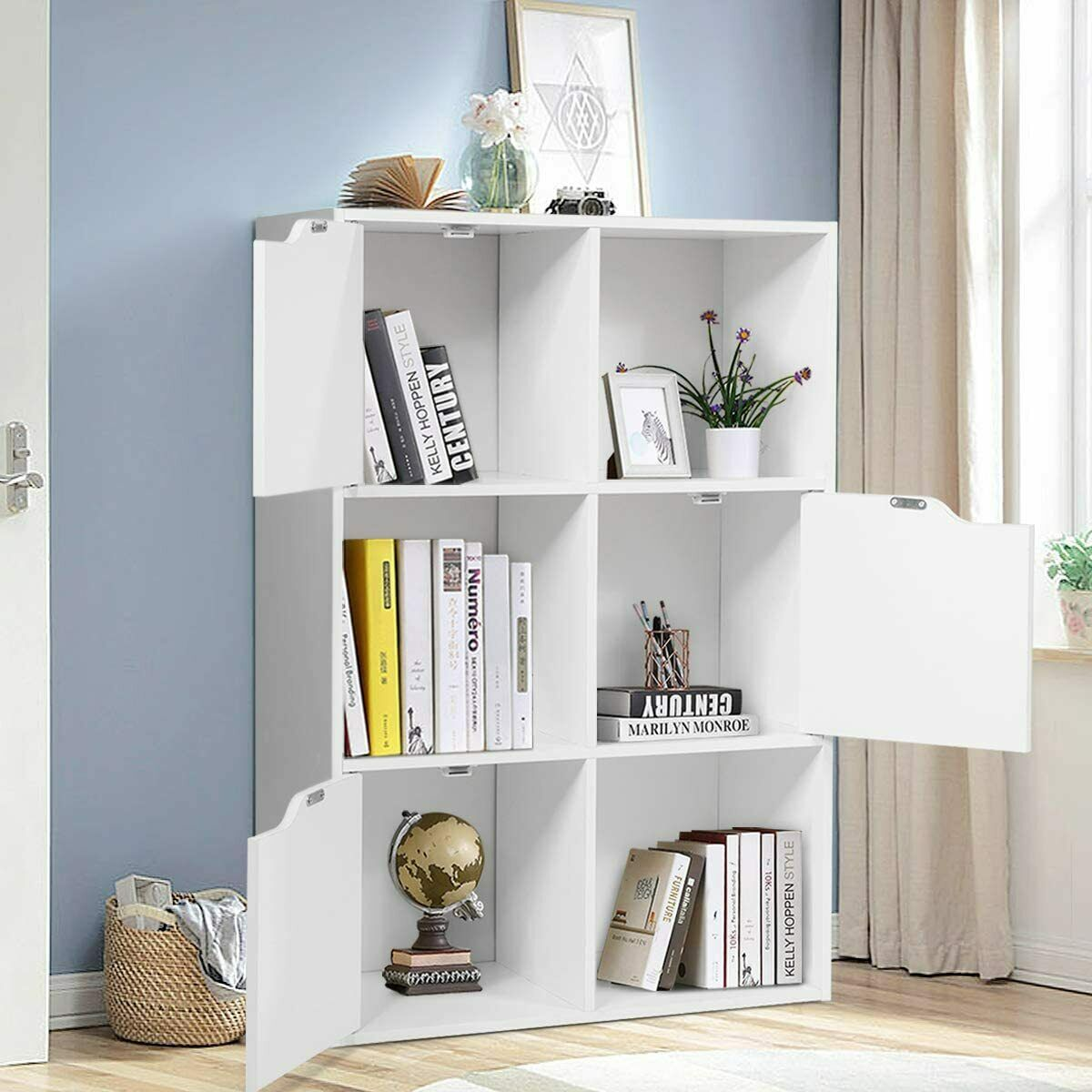 Ein weißes Aufbewahrungsmöbel mit Büchern, einem Globus und Dekoration.