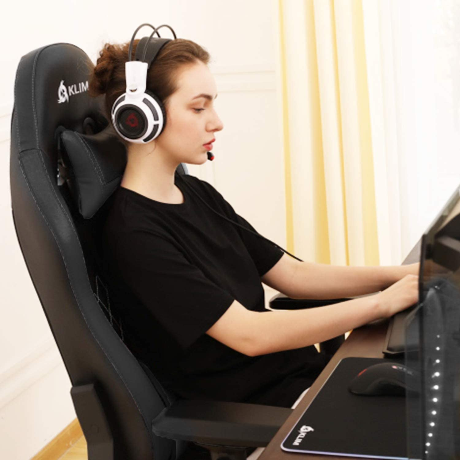 Frau spielt mit Kopfhörern und einem Gaming-Stuhl.