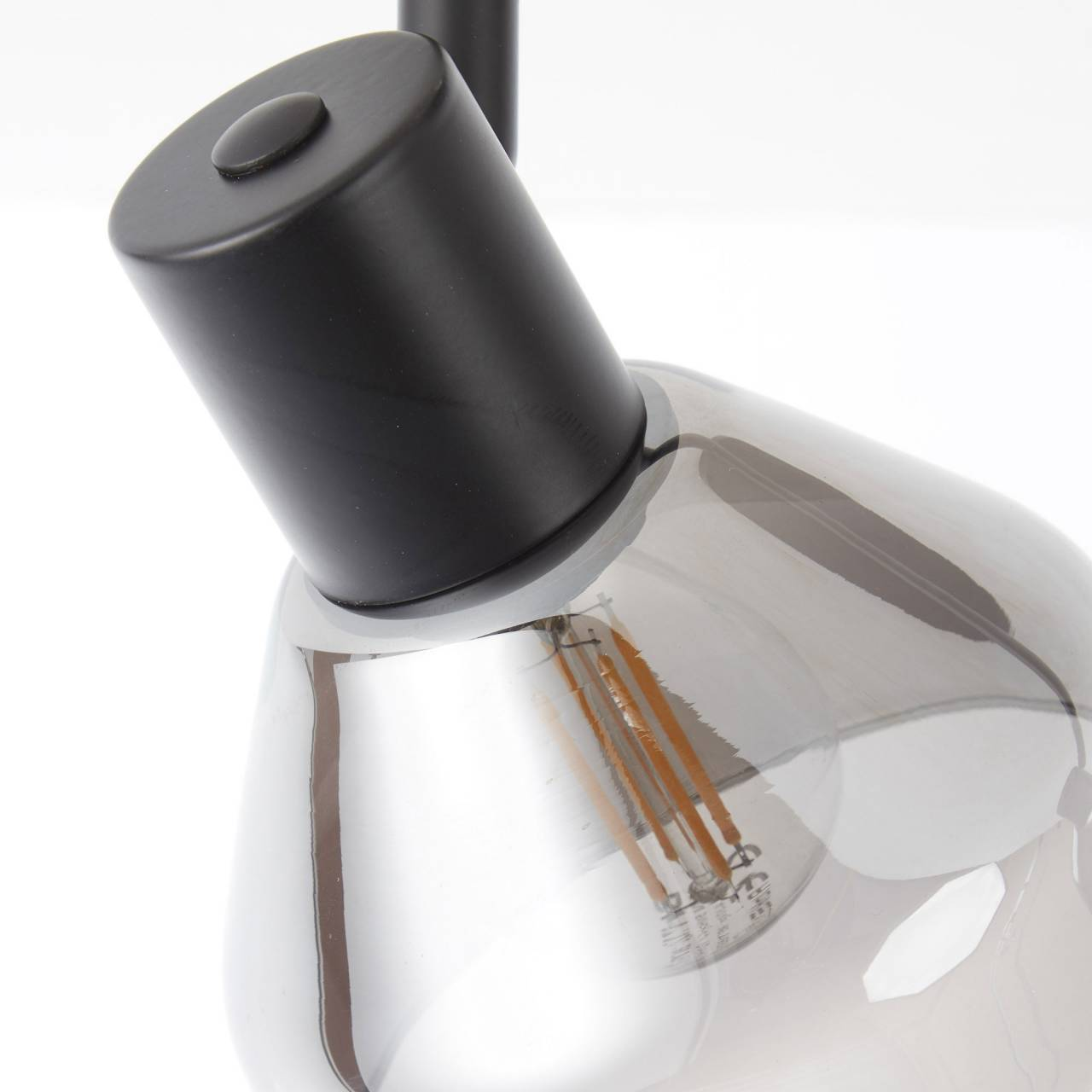 Schwarze Lampe mit Glasschirm, Glühbirne sichtbar.