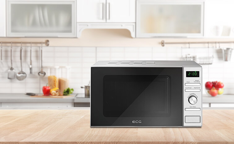 Kuchenka mikrofalowa na drewnianym stole, tło kuchni. Kuchenka jest czarna i srebrna.