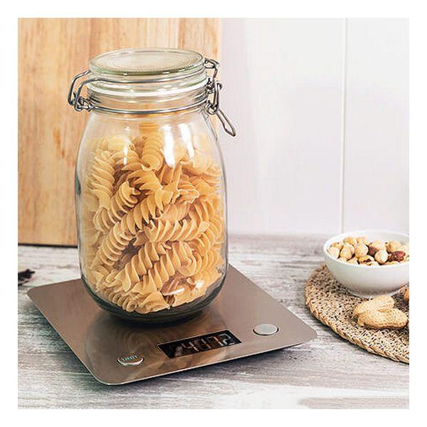Makaron w szklanym słoiku na wadze, z orzechami i składnikami.