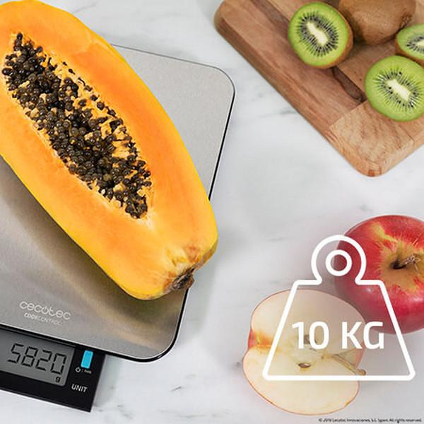 Połówka papai na wadze z wynikiem 5820 g. Plastry kiwi i jabłko obok wagi.