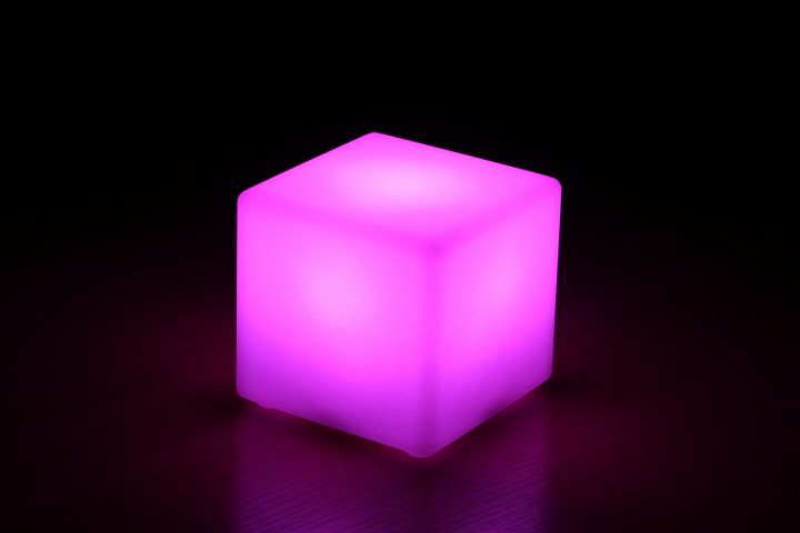 Ein leuchtender Würfel, beleuchtet mit rosa Licht, auf schwarzem Hintergrund.
