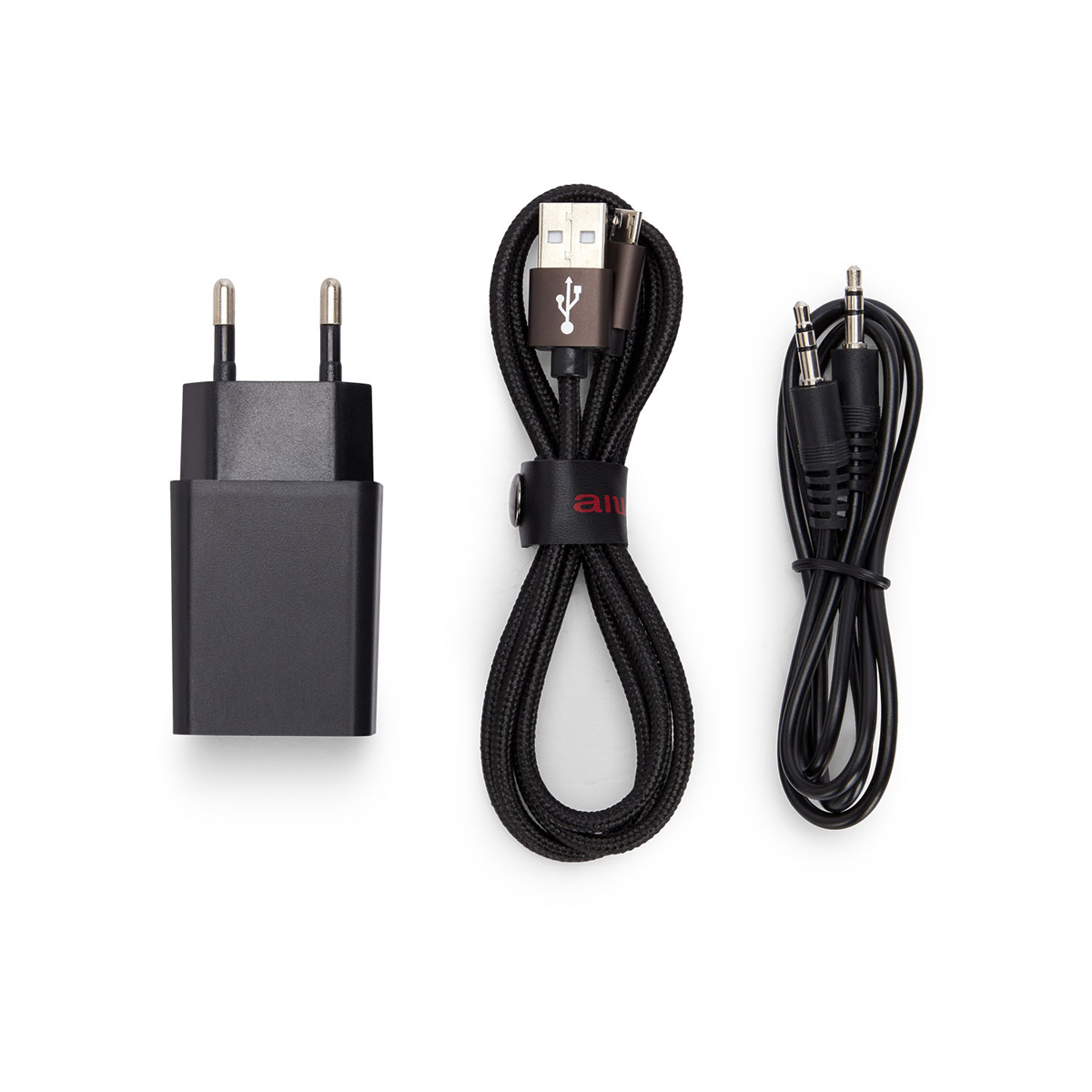 Ladegerät, USB-Kabel und Audiokabel auf Weiß. Schwarzes Ladegerät, braunes USB-Kabel, schwarzes Audiokabel.
