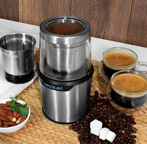 Młynek do kawy z mieloną kawą w szklanym słoiku z ziarnami kawy i filiżankami.