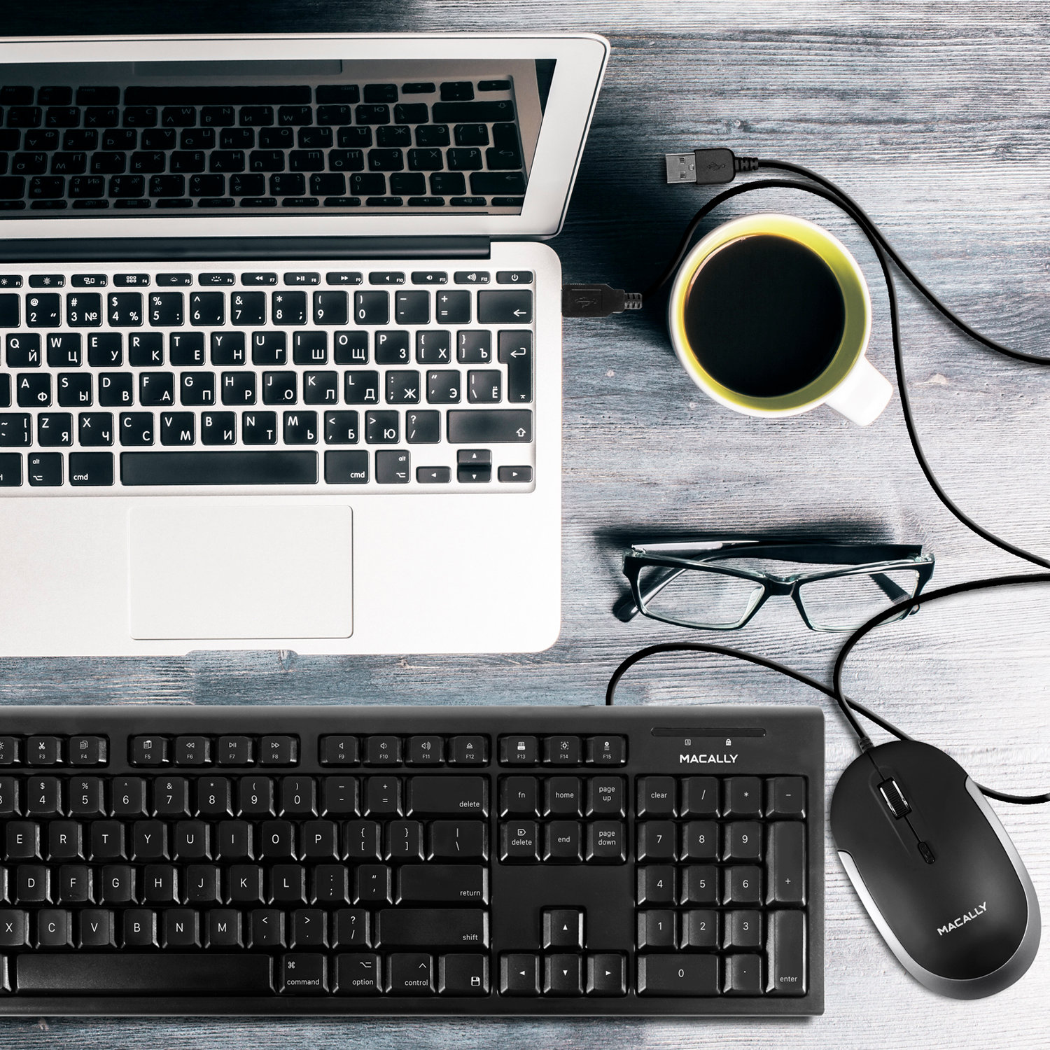 Laptop, tastiera, mouse e tazza di caffè su una scrivania di legno.