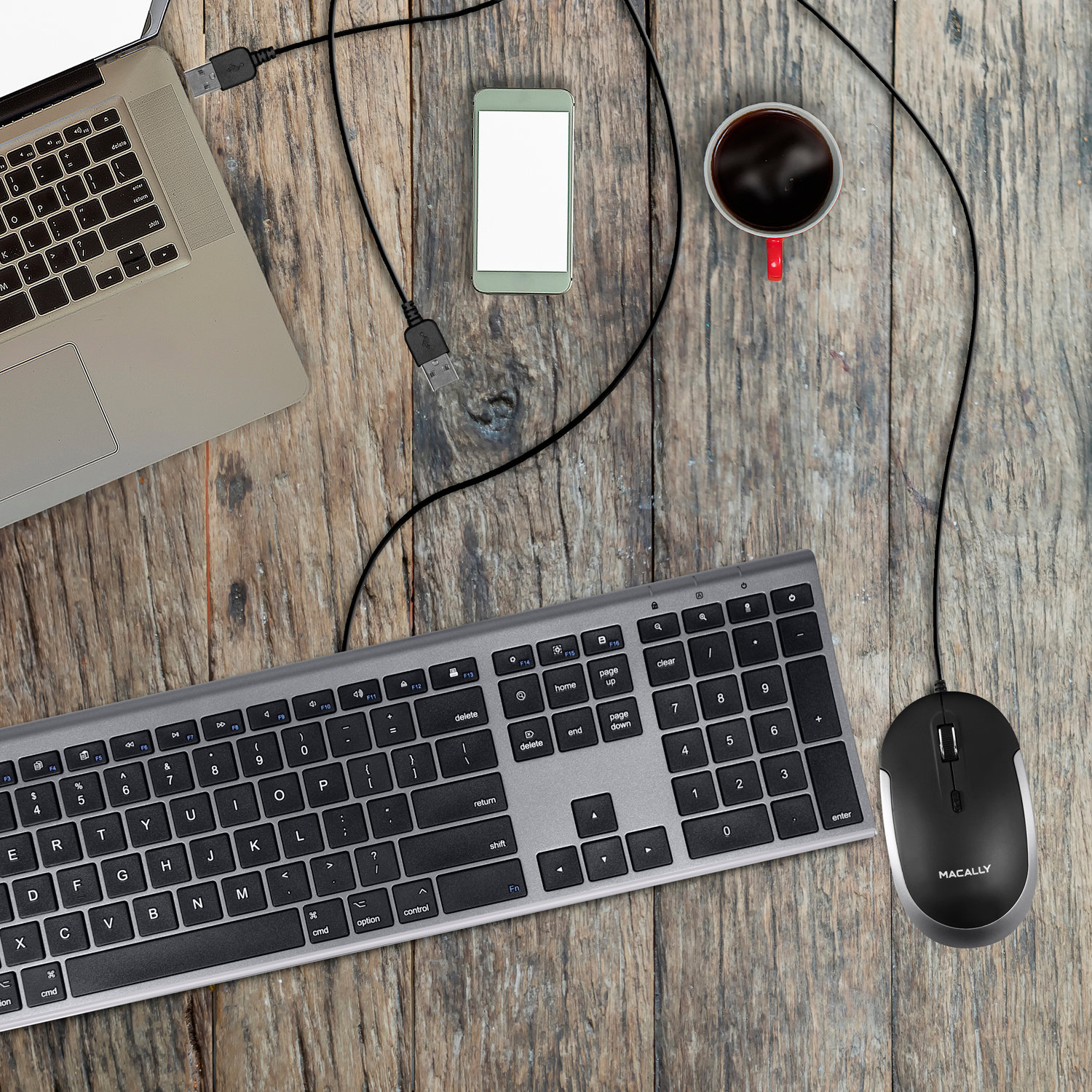 Scrivania in legno con laptop, tastiera, telefono, mouse e tazza di caffè.