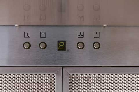 Nahaufnahme eines Edelstahl-Dunstabzugshauben-Bedienfelds mit Tasten und Display.
