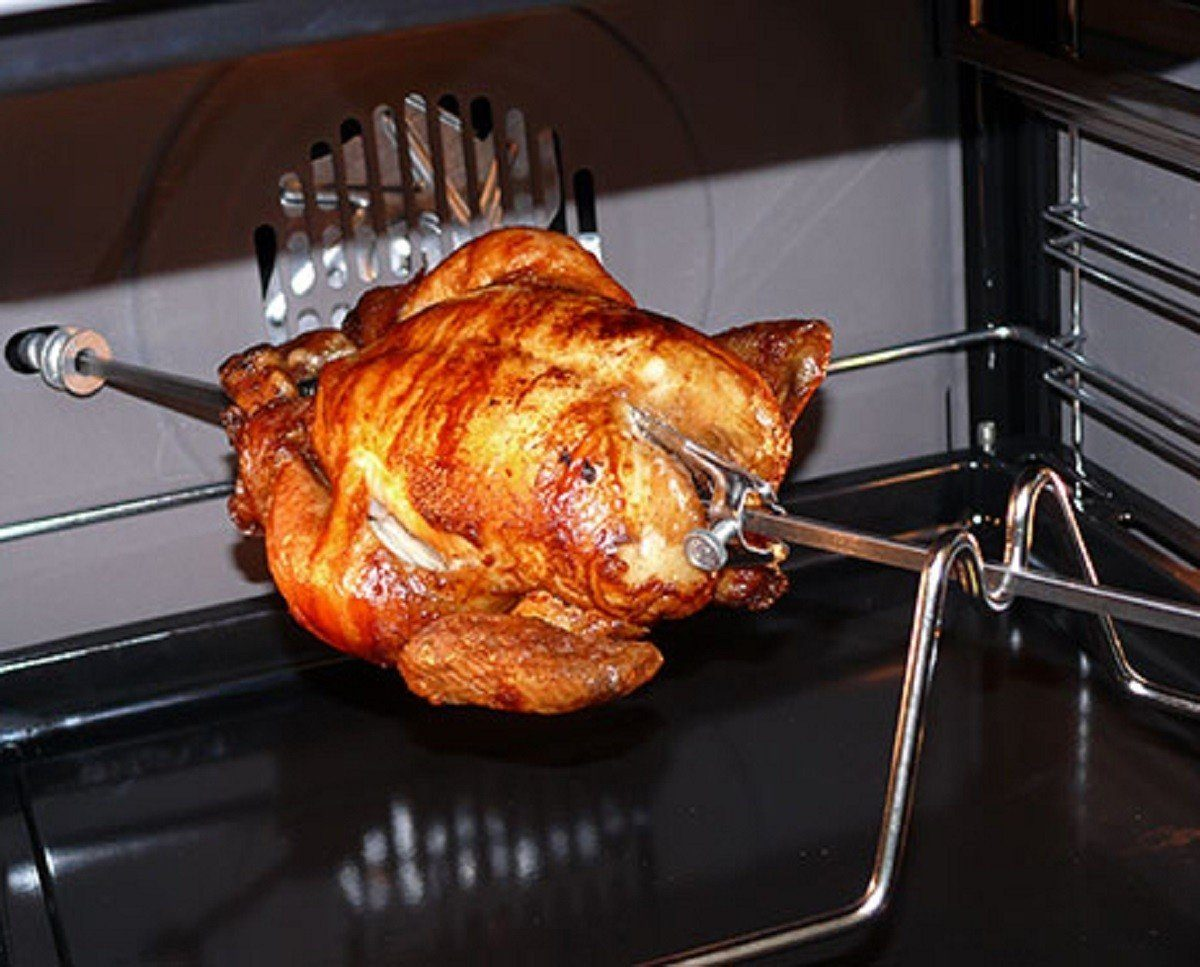 Gebratenes Huhn auf einem Drehspieß im Ofen, goldbraun und fertig.