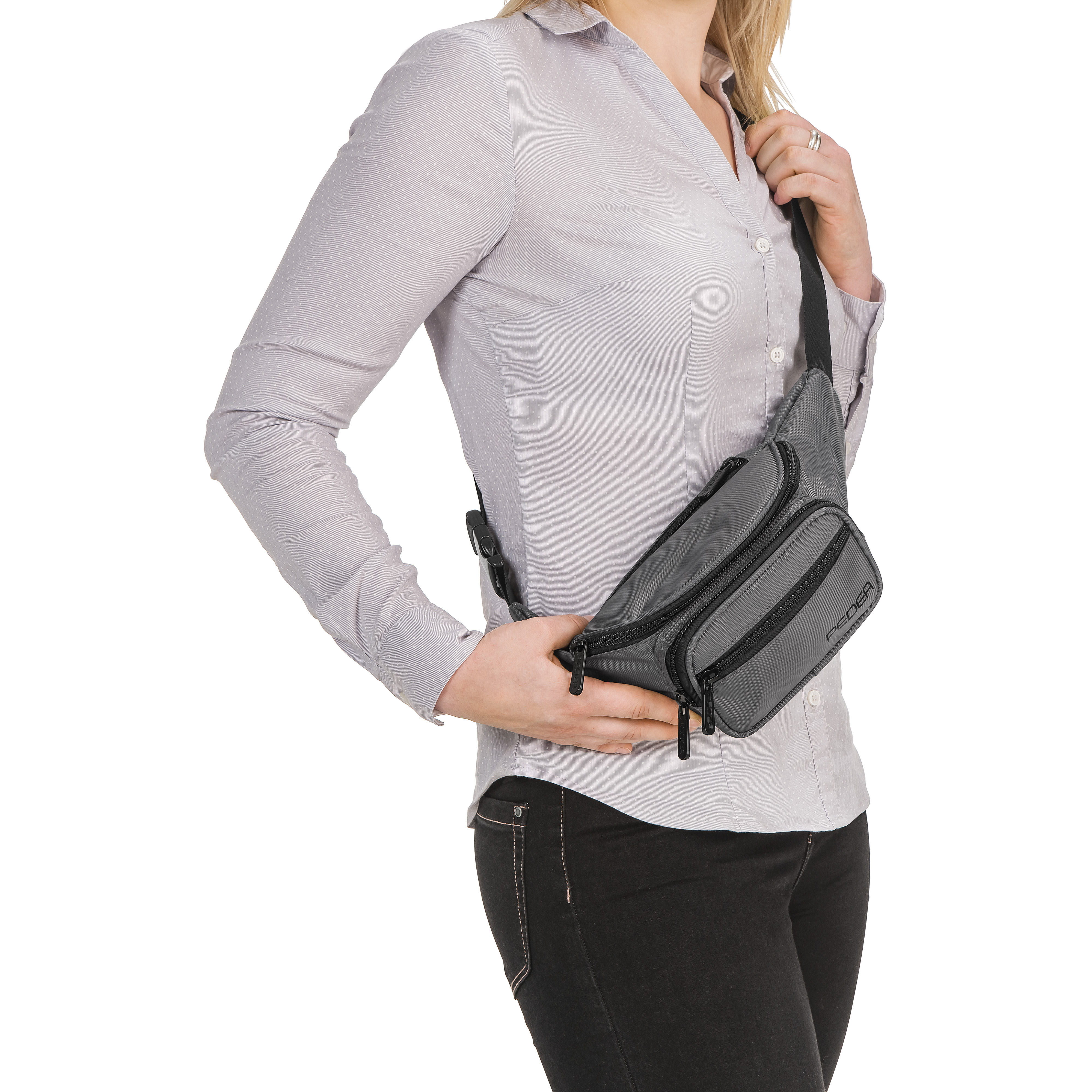 Eine Frau, die eine graue Bauchtasche trägt. Sie trägt auch ein graues Hemd mit Knöpfen und eine schwarze Hose.