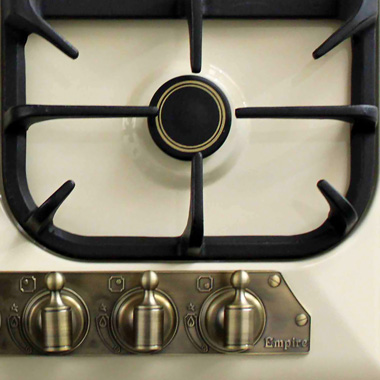 Primer plano de la superficie de una cocina de gas. Incluye quemadores, controles y la marca "Empire".