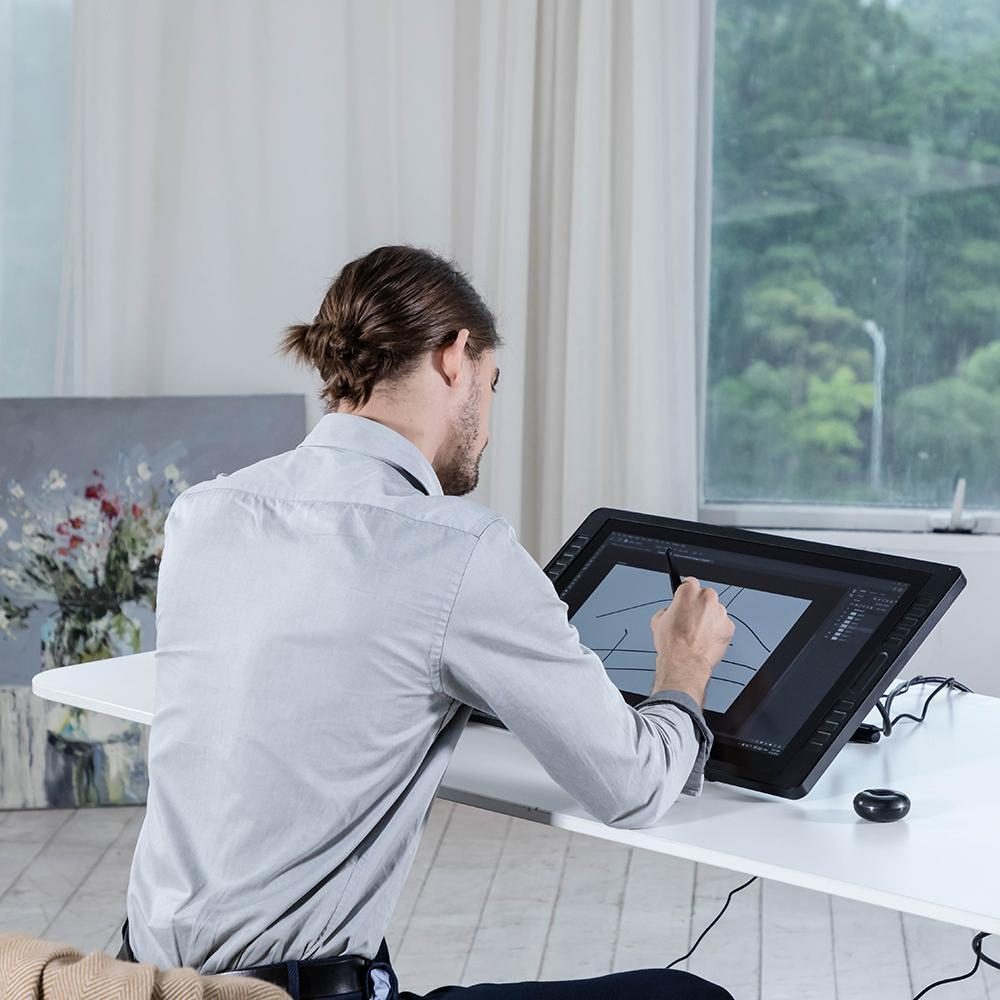 Ein Mann zeichnet mit einem Stift auf einem Tablet an einem weißen Schreibtisch.