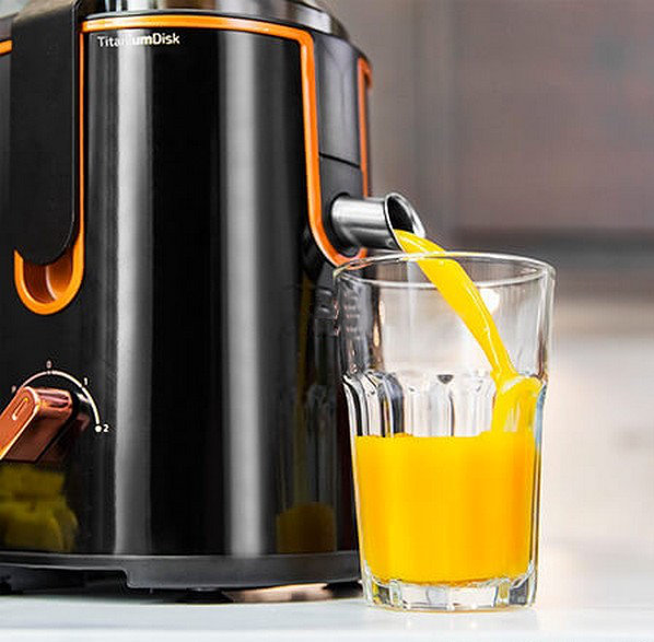 Il succo scorre da un'estrattore in un bicchiere. L'estrattore è nero e arancione.