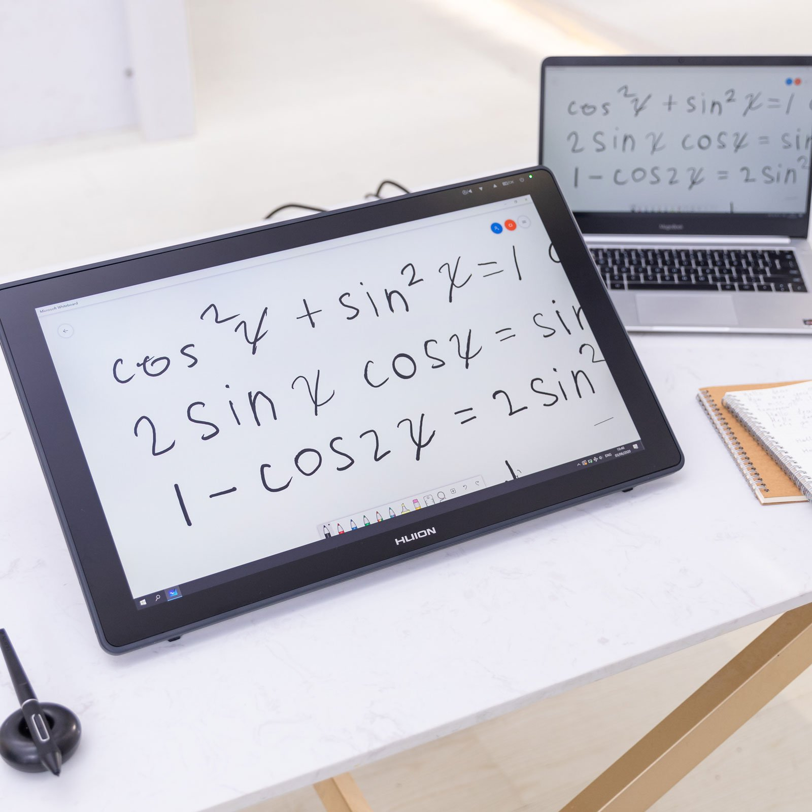 Tablet auf Schreibtisch mit Matheformeln, Laptop im Hintergrund.