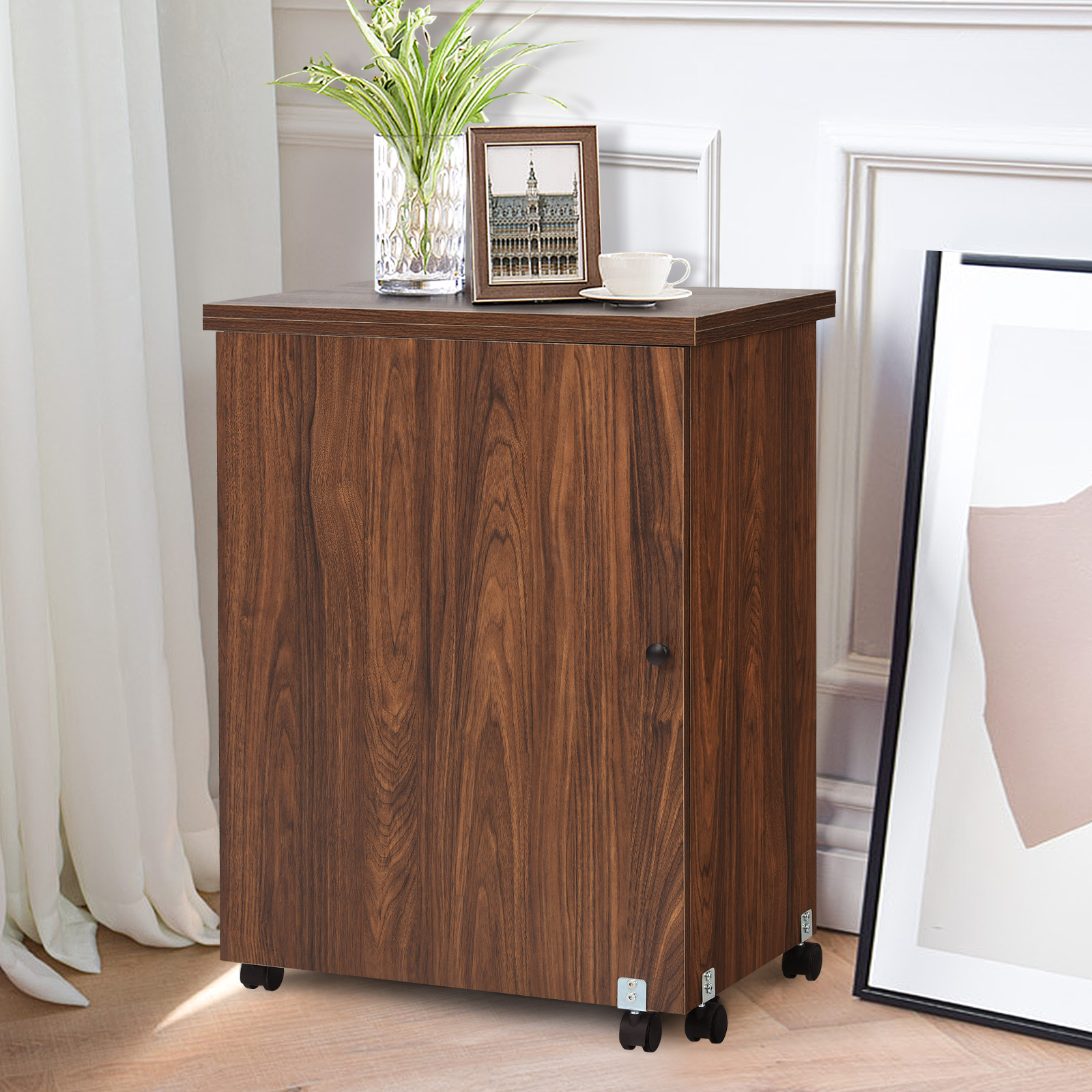 Holzschrank auf Rädern. Ein gerahmtes Bild, Vase mit Pflanzen und eine Tasse oben drauf.