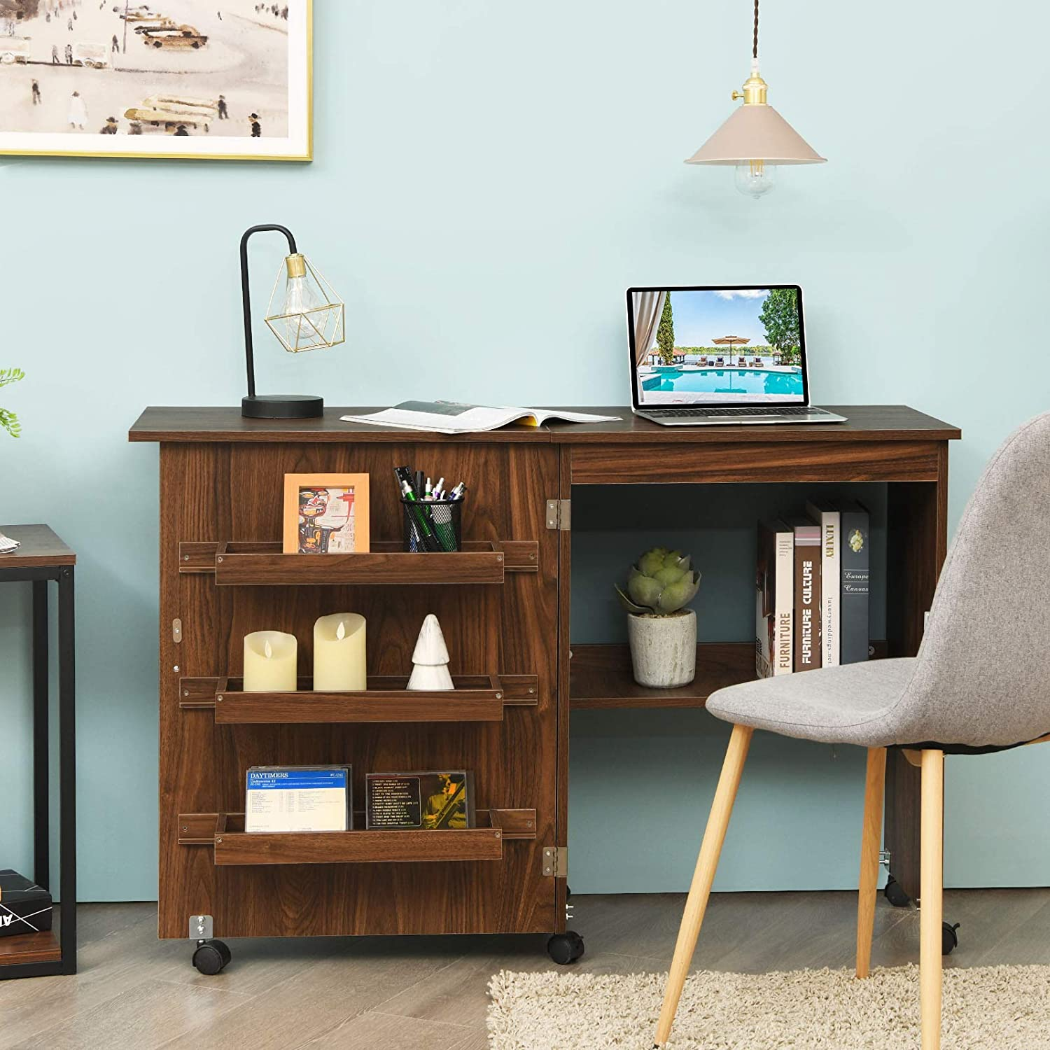 Holzschreibtisch mit Laptop, Büchern, Kerzen und Lampe. Hintergrund blau.