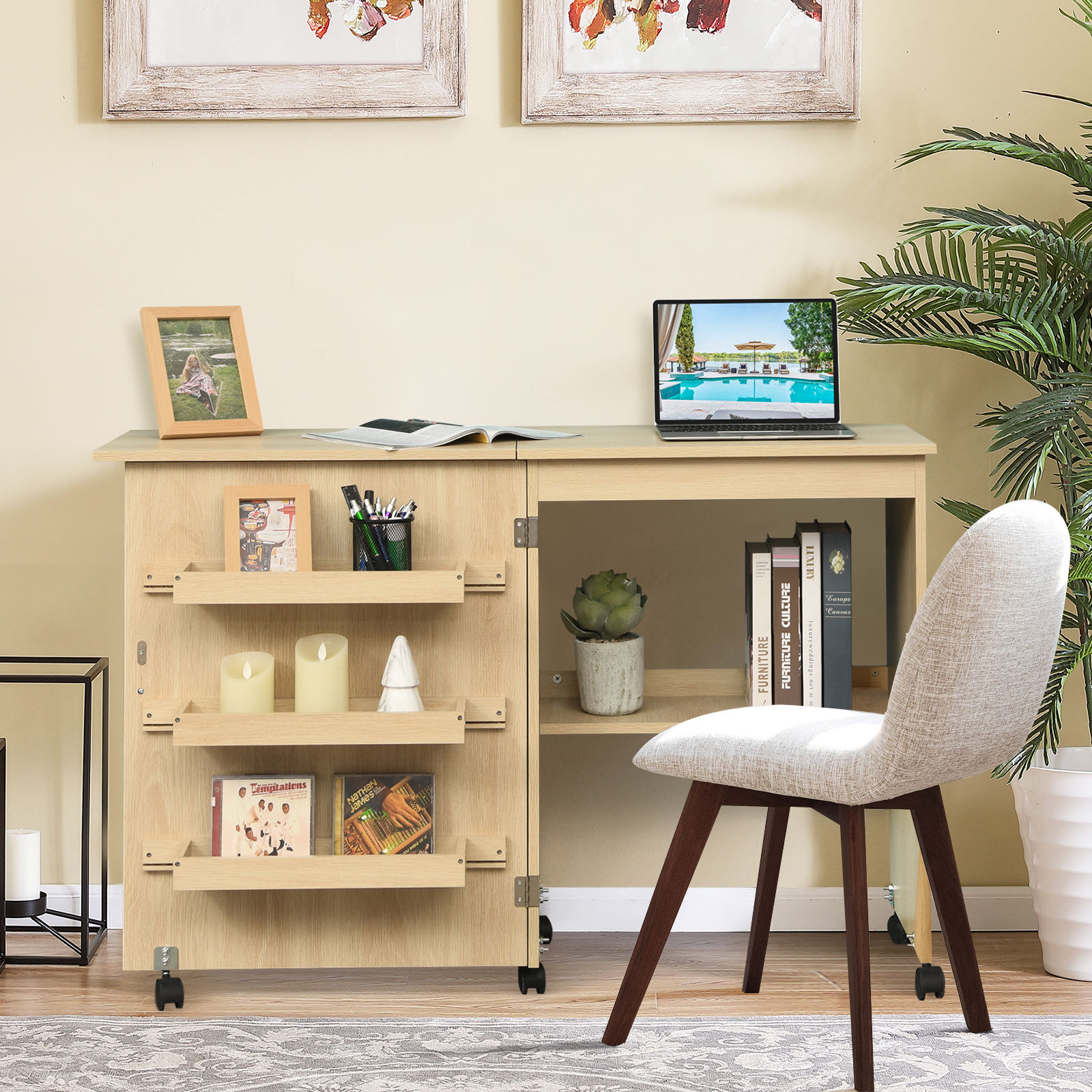 Ein Schreibtisch mit Laptop, Büchern, Bildern, Stiften, Kerzen und einem Stuhl. Der Hintergrund ist hellbeige.