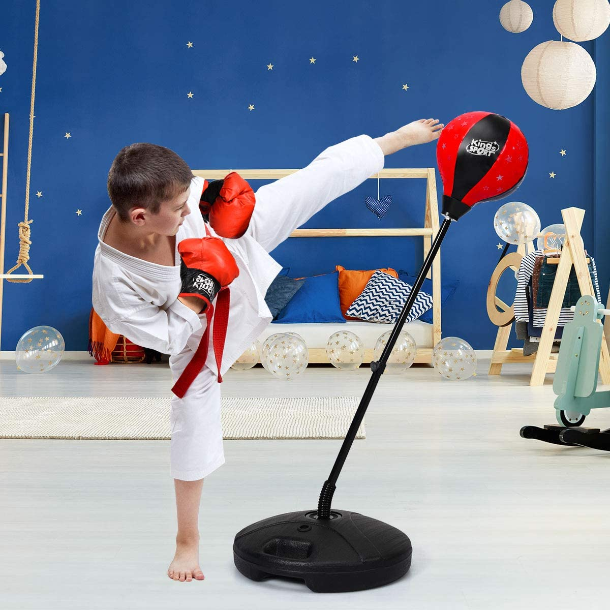 Junge in Karate-Anzug tritt einen roten Boxsack in einem Raum mit Dekorationen.