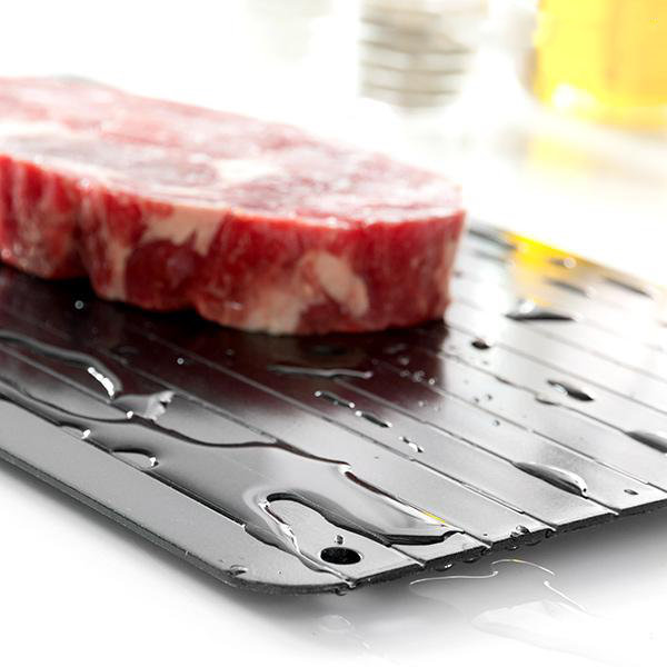 Rohes Fleisch auf einem schwarzen Tablett. Wassertropfen sind sichtbar. Hintergrund ist unscharf.