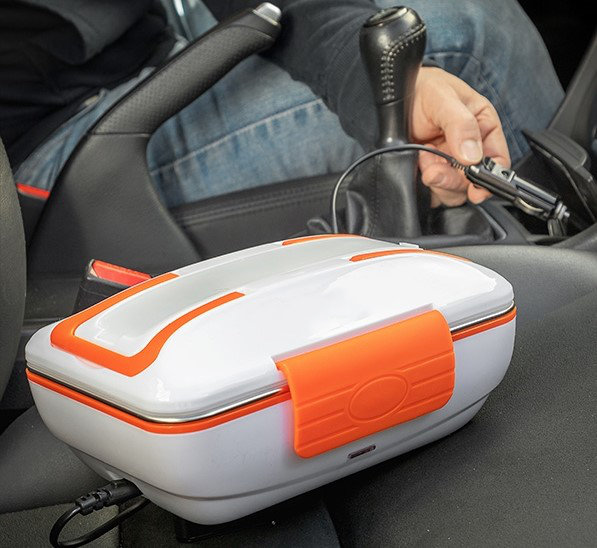 Weiß-oranger Auto-Speisenwärmer in einem Auto. Person im Auto, schwarze Innenausstattung.