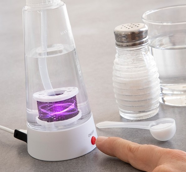 Ionizador de agua con sal, cuchara y botón de encendido.