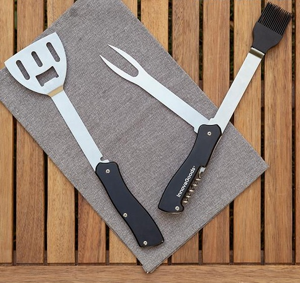 Grillwerkzeuge auf einem grauen Tuch auf einer Holzoberfläche.