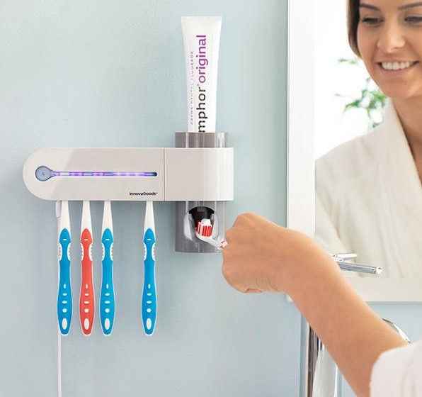 Un soporte para cepillos de dientes con cepillos y una mujer cepillándose los dientes en un espejo.
