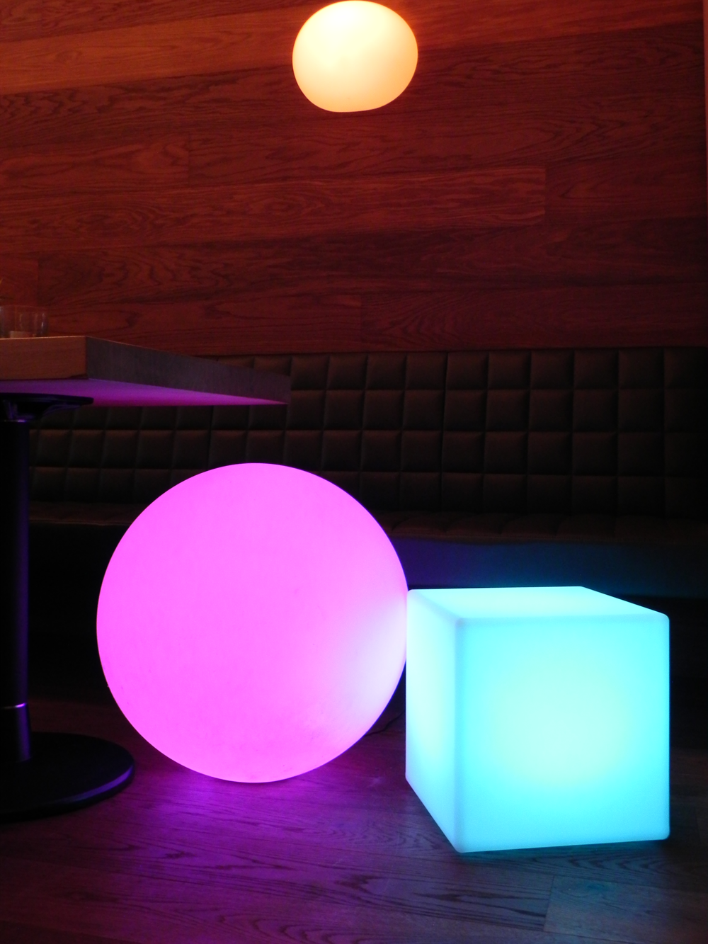 Raum mit pinken und blauen leuchtenden Kugeln und Würfel. Holz-Wand im Hintergrund.