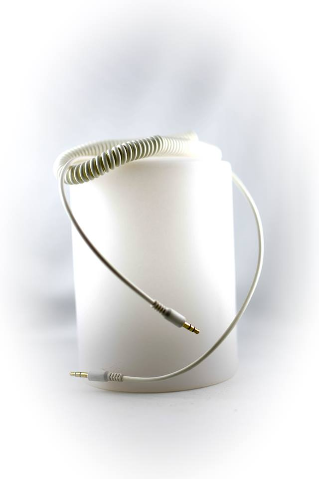 Ein weißes Spiralkabel für Kopfhörer. Das Kabel befindet sich auf einem weißen zylindrischen Objekt.