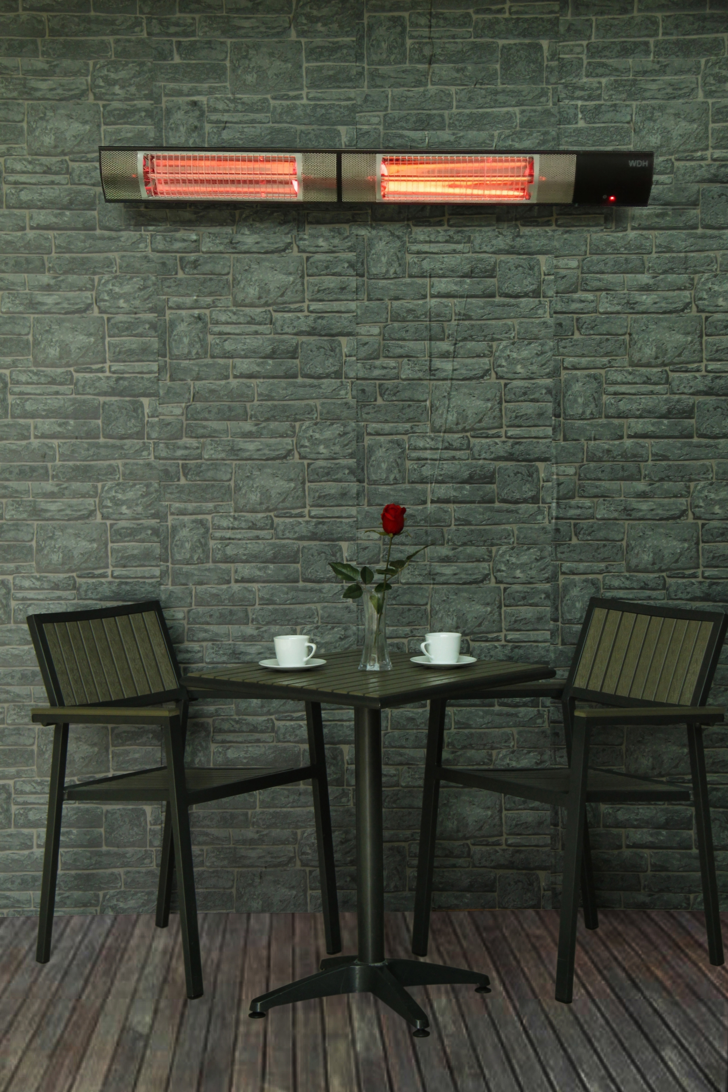 Szene im Freien mit zwei Stühlen, Tisch und roter Rose in Vase. Wandheizung oben.