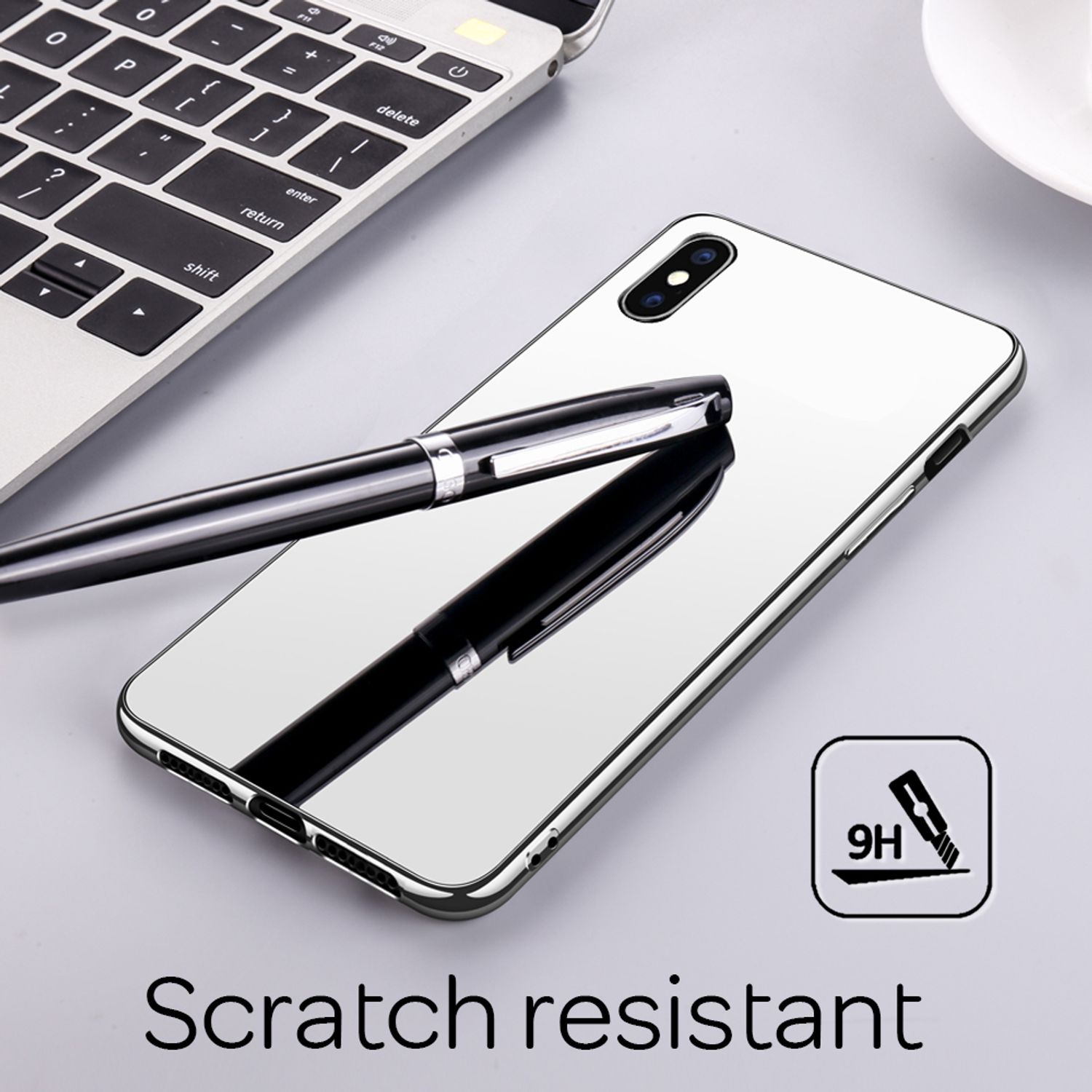 Eine reflektierende Handyhülle mit Stift und Laptop. Die Oberfläche des Telefons reflektiert die Umgebung.