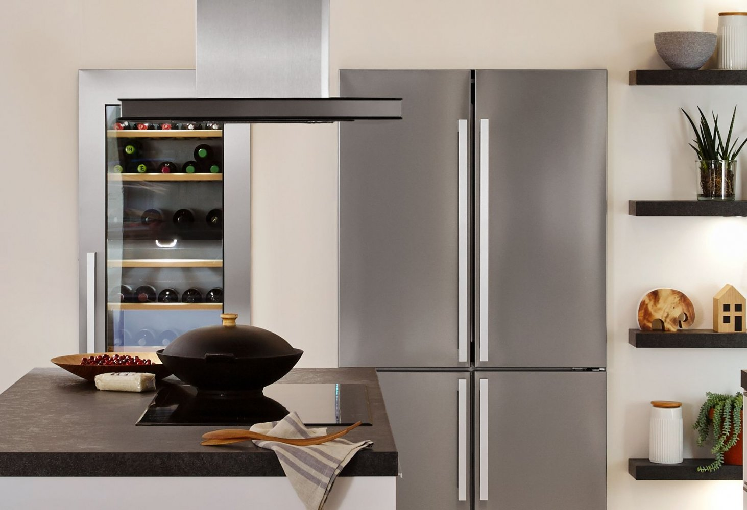 Nowoczesna kuchnia ze sprzętem ze stali nierdzewnej, lodówką na wino i czarnym blatem.