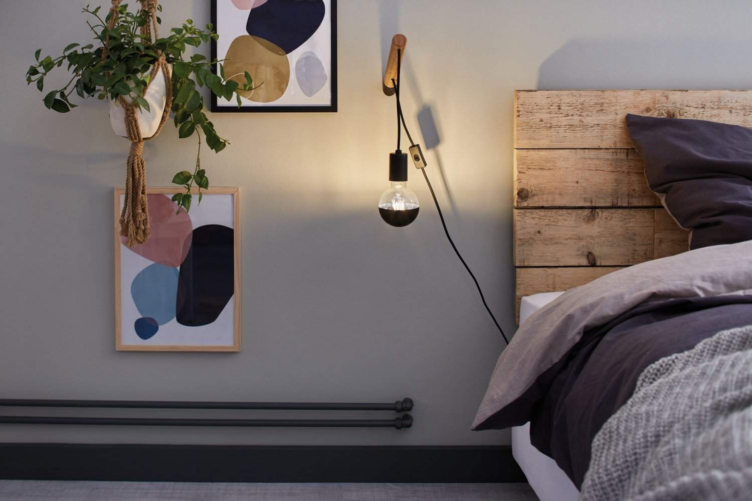 Scena sypialni z łóżkiem, dekoracją ścienną i lampą wiszącą. Zielona ściana i jasne łóżko.