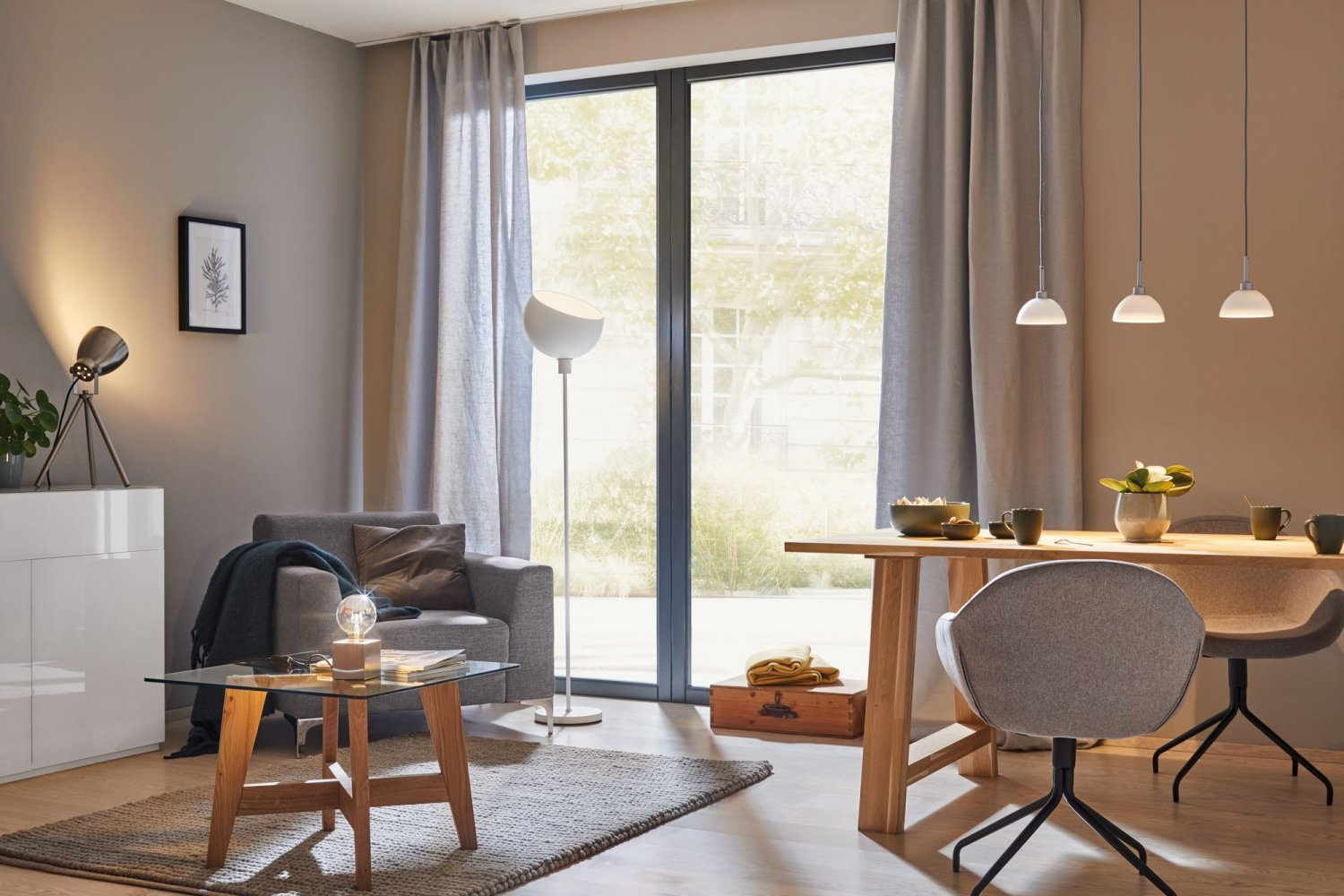 Ein Wohnzimmer mit neutralen Farben, Sofa, Tisch, Teppich und Beleuchtung.