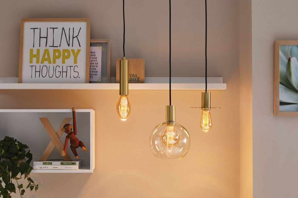 Drei hängende Leuchten mit goldenen Akzenten. Der Hintergrund ist ein neutraler, warmtoniger Raum.