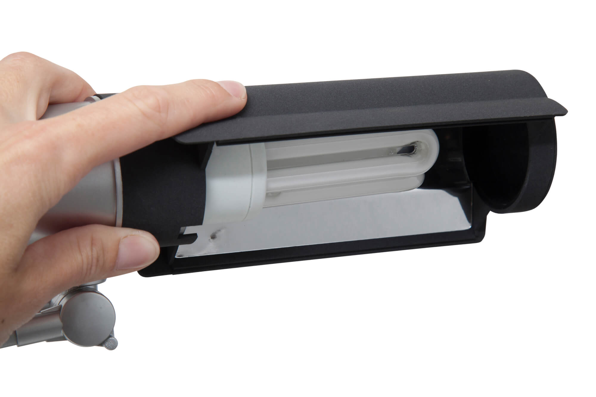 Ręka trzymająca czarną lampę, odsłaniająca świetlówkę. Tło jest białe.