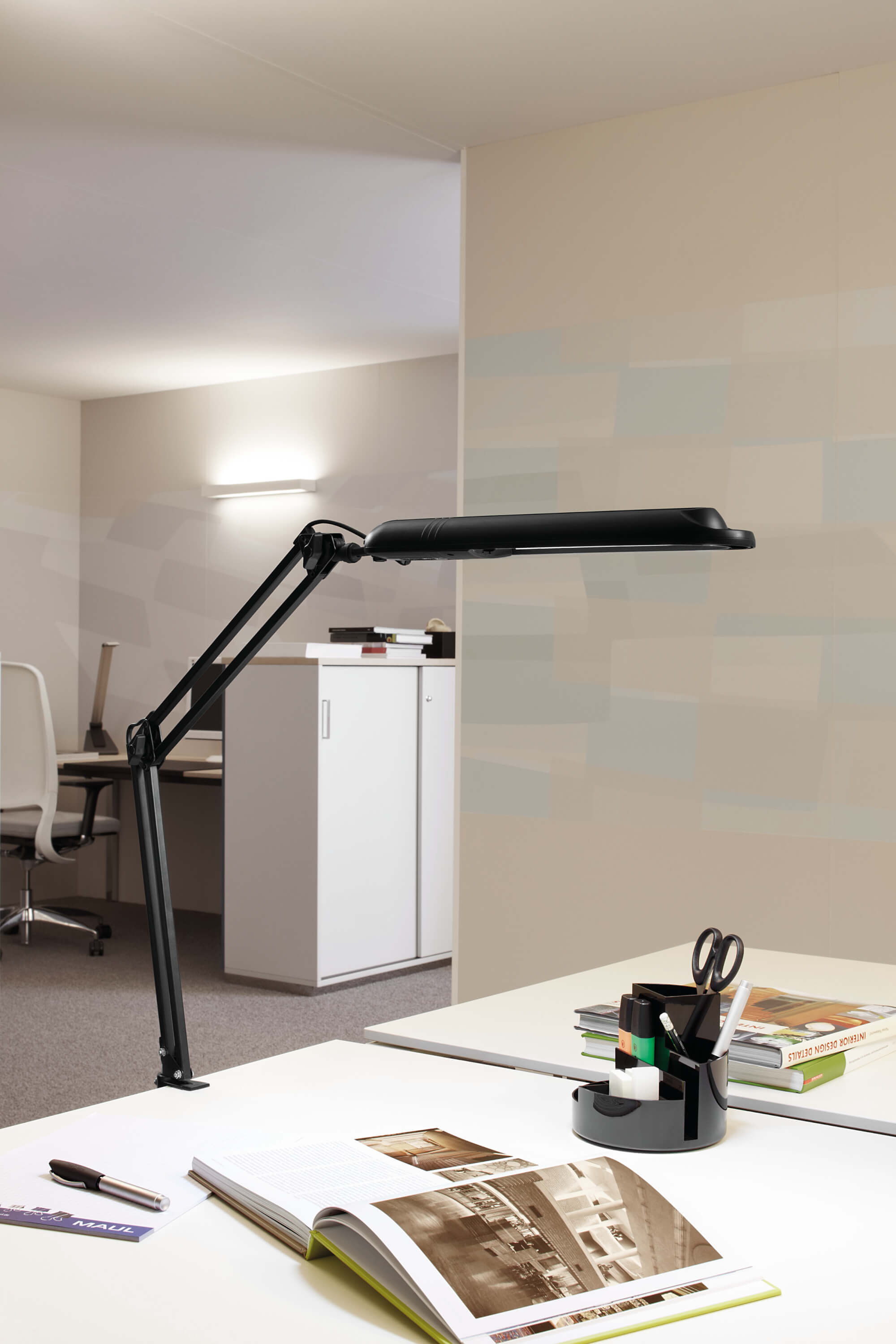 Schwarze Schreibtischlampe über weißem Schreibtisch mit Bürobedarf.