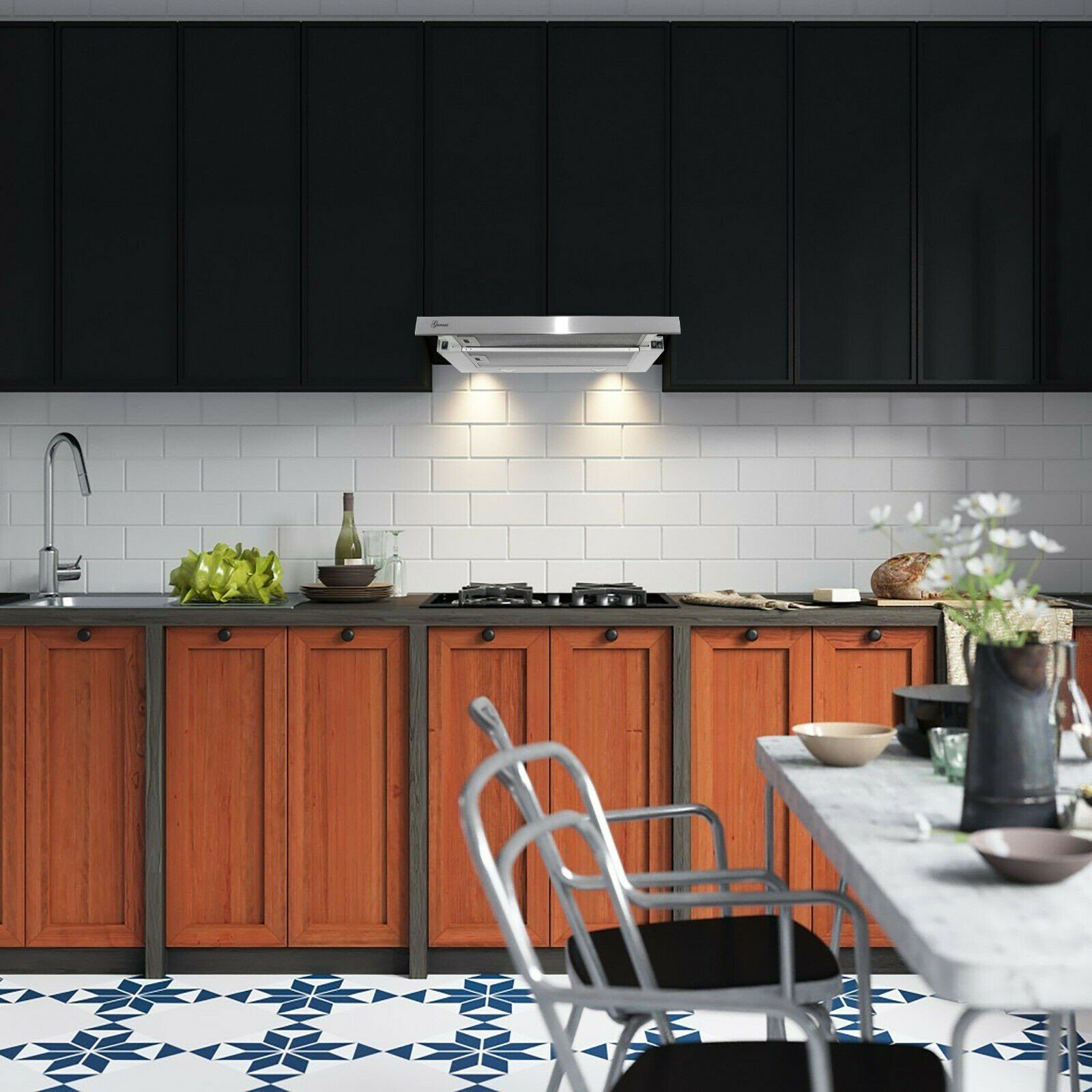 Cocina con gabinetes negros, salpicadero de azulejos blancos y campana extractora de acero inoxidable.
