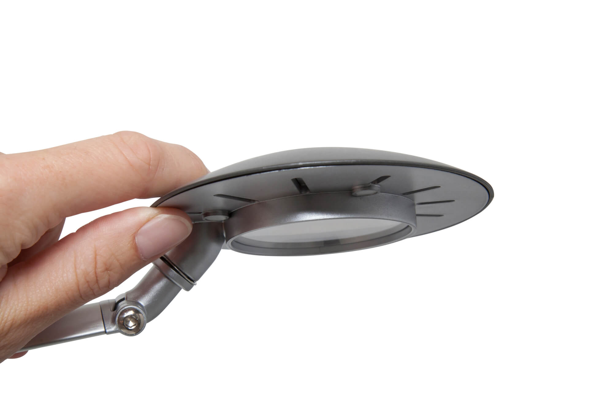 Ręka trzyma srebrną głowicę lampy. Głowica lampy jest okrągła z lupą.