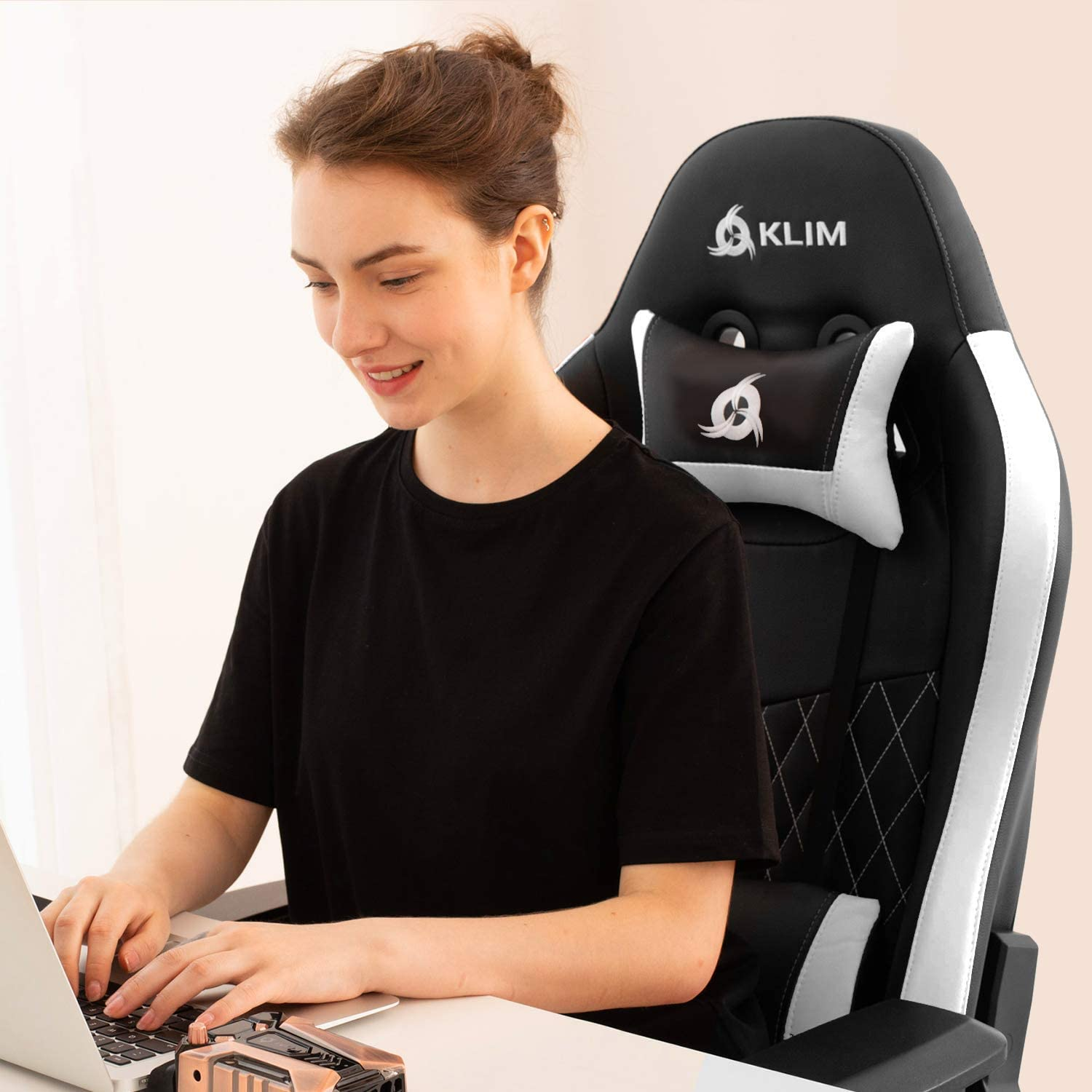 Frau in schwarzem Shirt, die einen Laptop benutzt, auf Gaming-Stuhl sitzt.