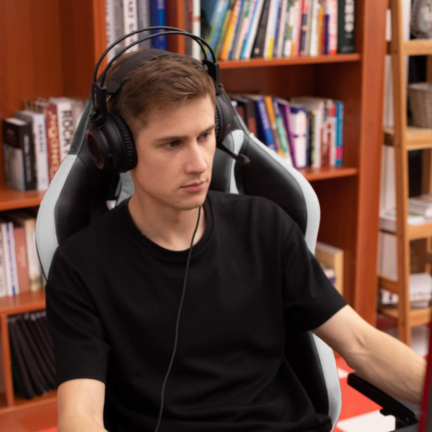 Mann mit Kopfhörern und Headset, der auf einen Bildschirm blickt, in einem Gaming-Stuhl sitzend.