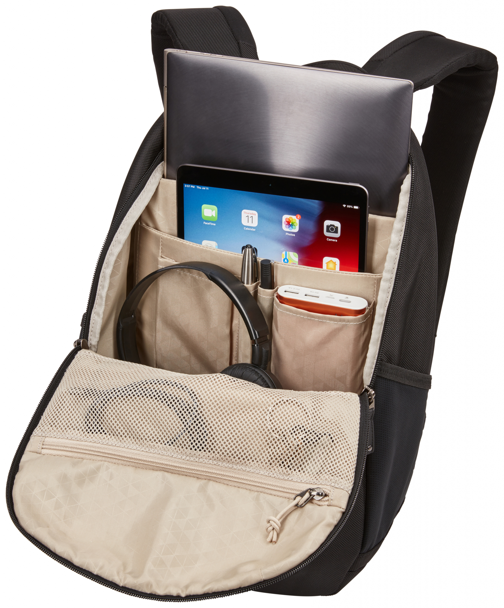 Schwarzer Rucksack offen, enthält Laptop, Tablet, Kopfhörer und andere Gegenstände. Weißer Hintergrund.