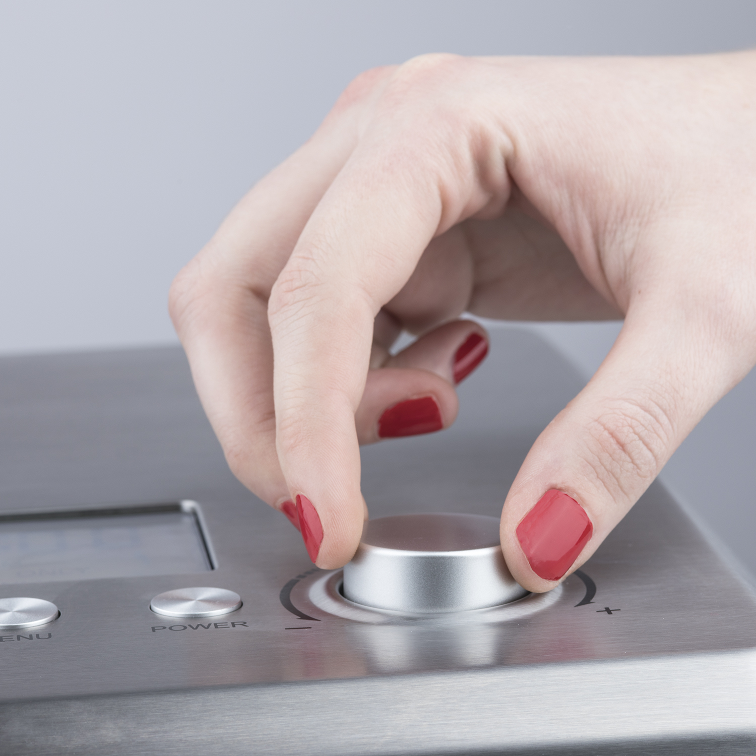 Dłoń obracająca pokrętło w maszynie, czerwone paznokcie.