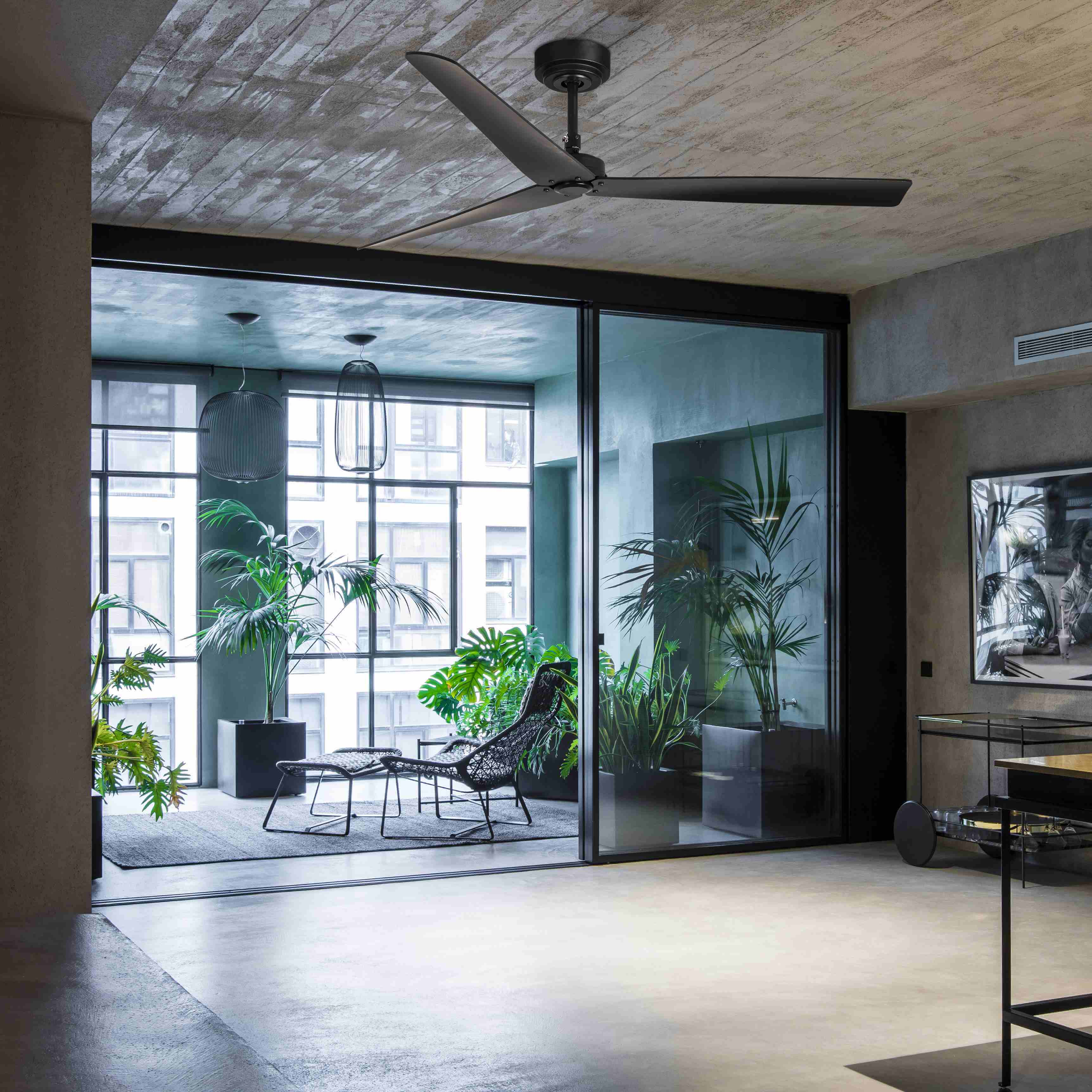 Ein modernes Interieur mit einem schwarzen Deckenventilator und großen Fenstern.