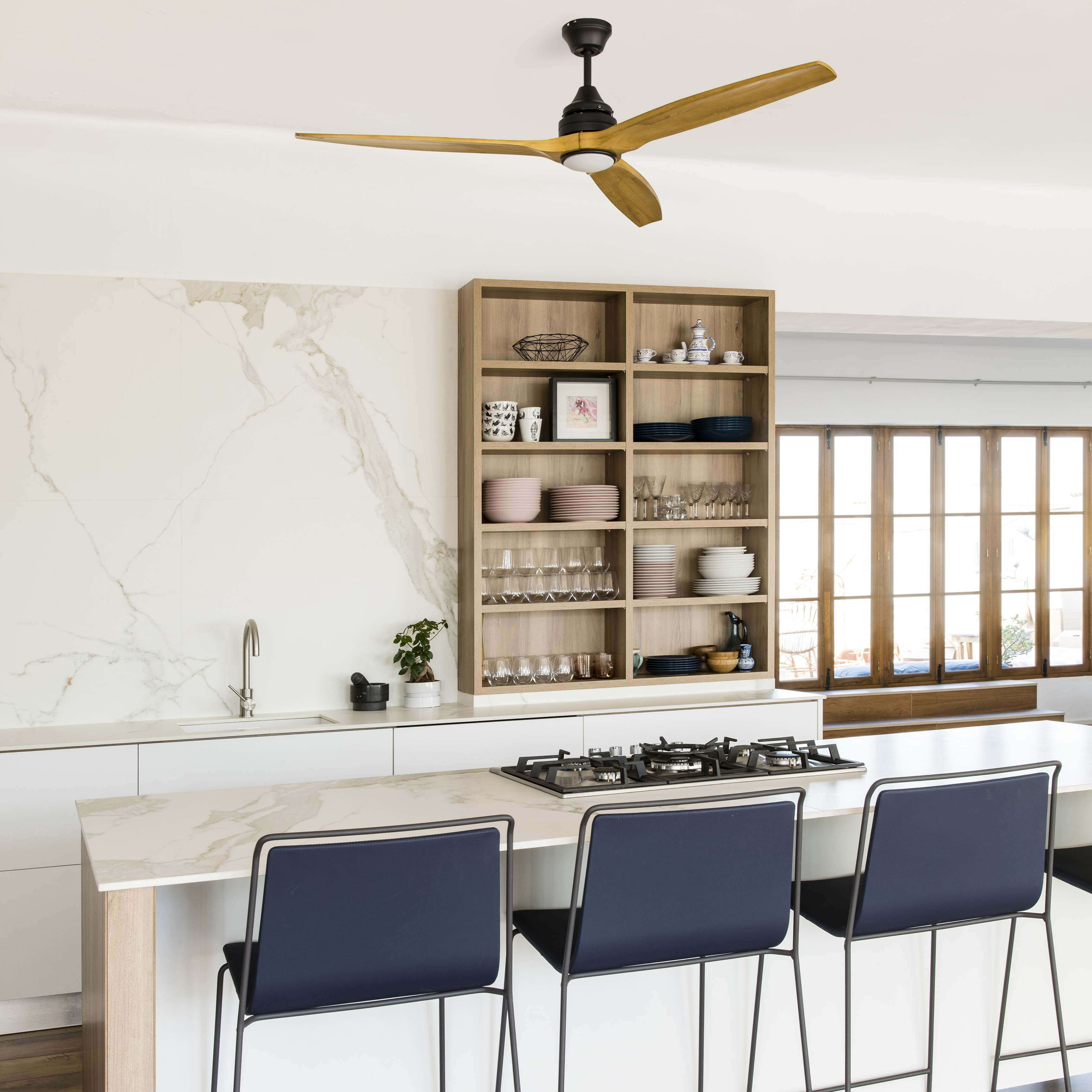 Una cucina con ventilatore a soffitto, mensole con piatti e sgabelli. Il colore è bianco.