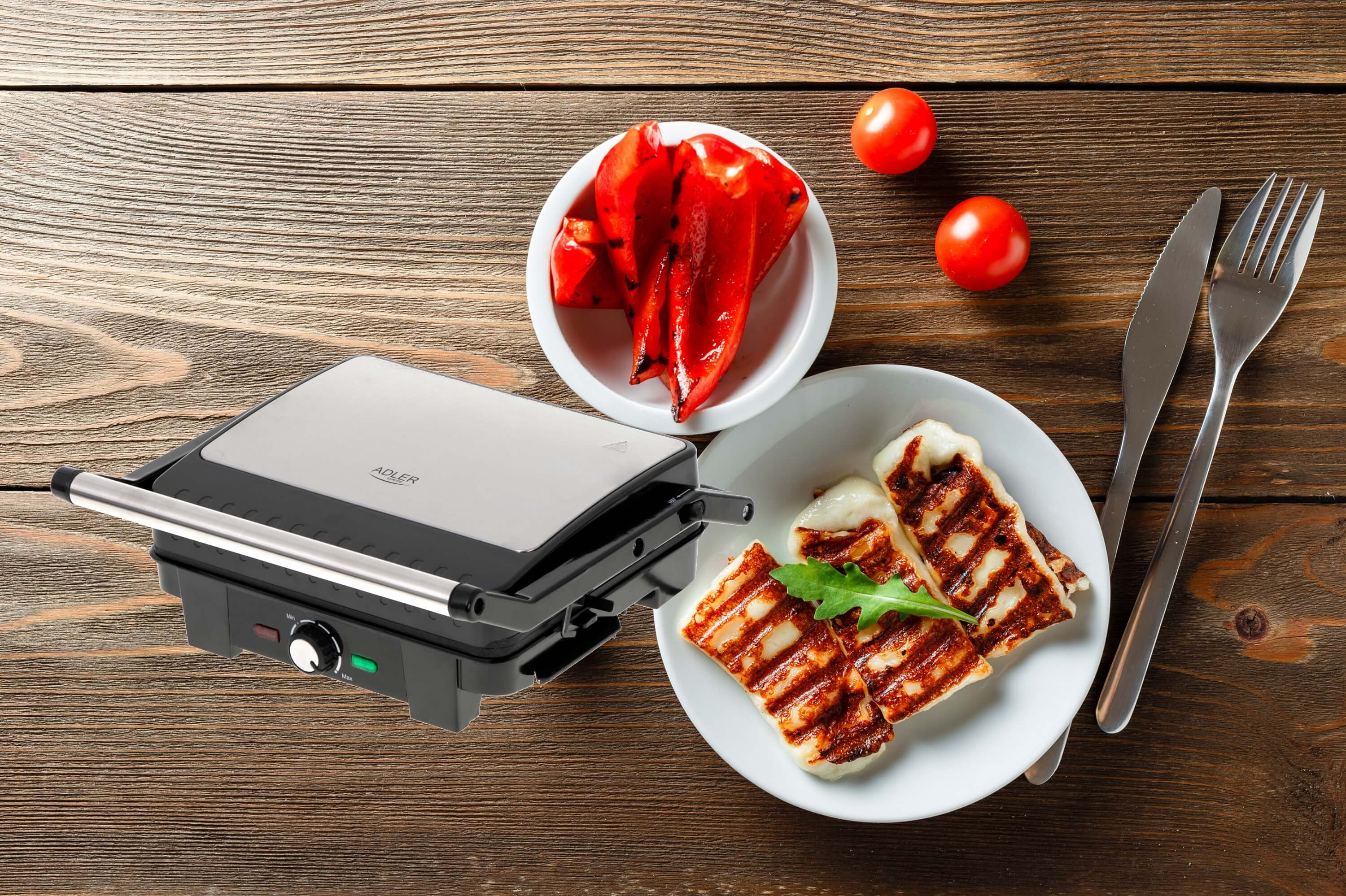 Grill z grillowanym serem halloumi, pieczoną papryką i pomidorami na drewnianym stole. Srebrny grill.