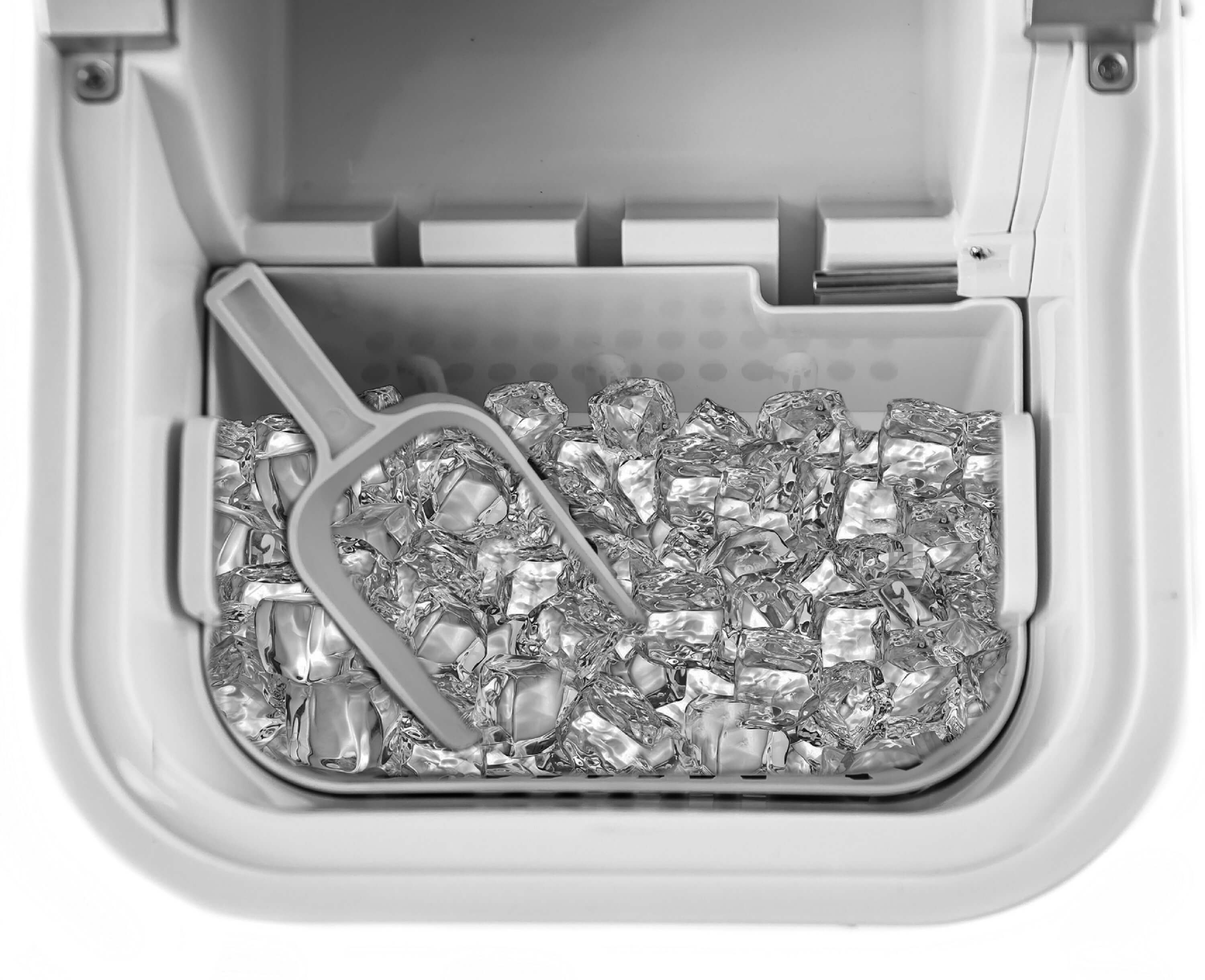 Wnętrze kostkarki do lodu, wypełnione kostkami lodu i szufelką po lewej stronie.